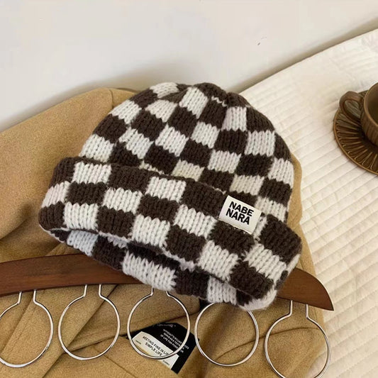 Brown and cream checkerboard knit beanie displayed on a chair