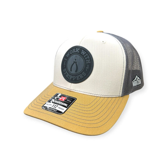 Angled view of I Work With Strippers patch hat by Horizon Hat Co. in mink beige/charcoal/amber gold showing the curved bill and side panels