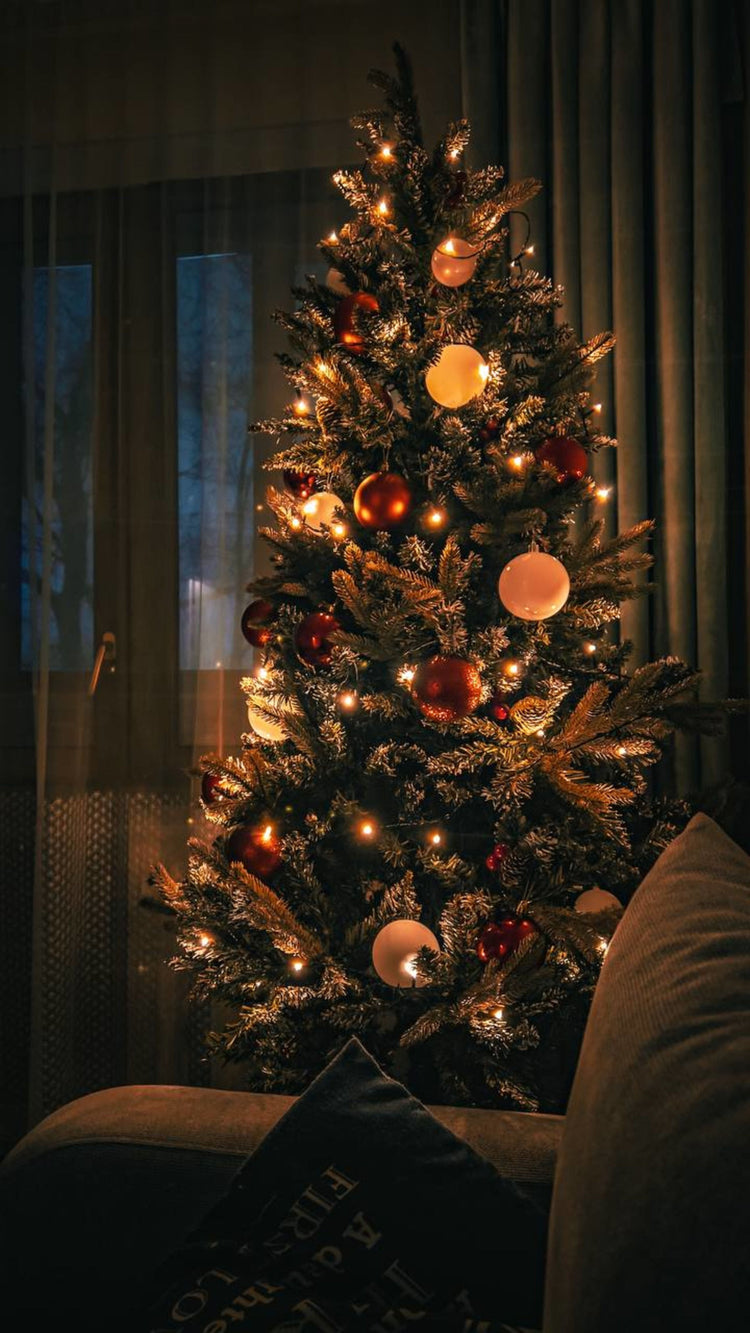 Decorated Christmas tree with warm lights and festive ornaments indoors.