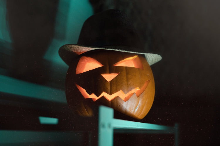 Glowing Halloween jack-o-lantern topped with a black pointed witch hat.
