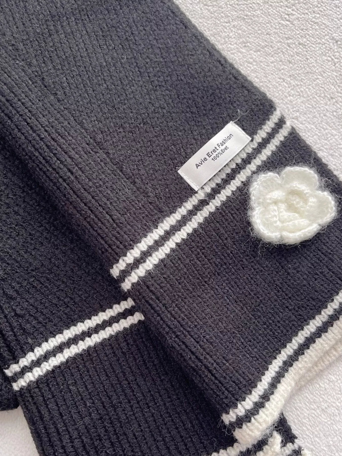 Women's Contrast Trim Knitted Scarf with Camellia Decor — close view of camellia applique and contrast edge stripes