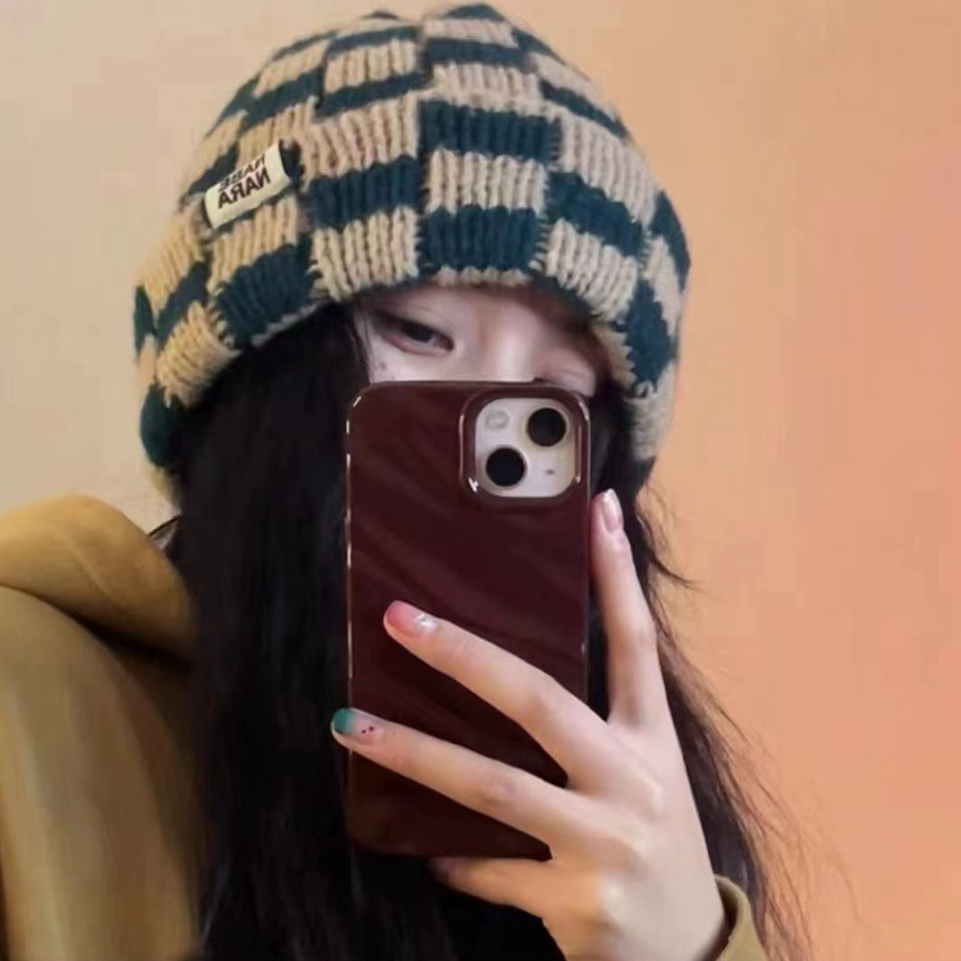 Adult wearing a beige and dark green checked beanie