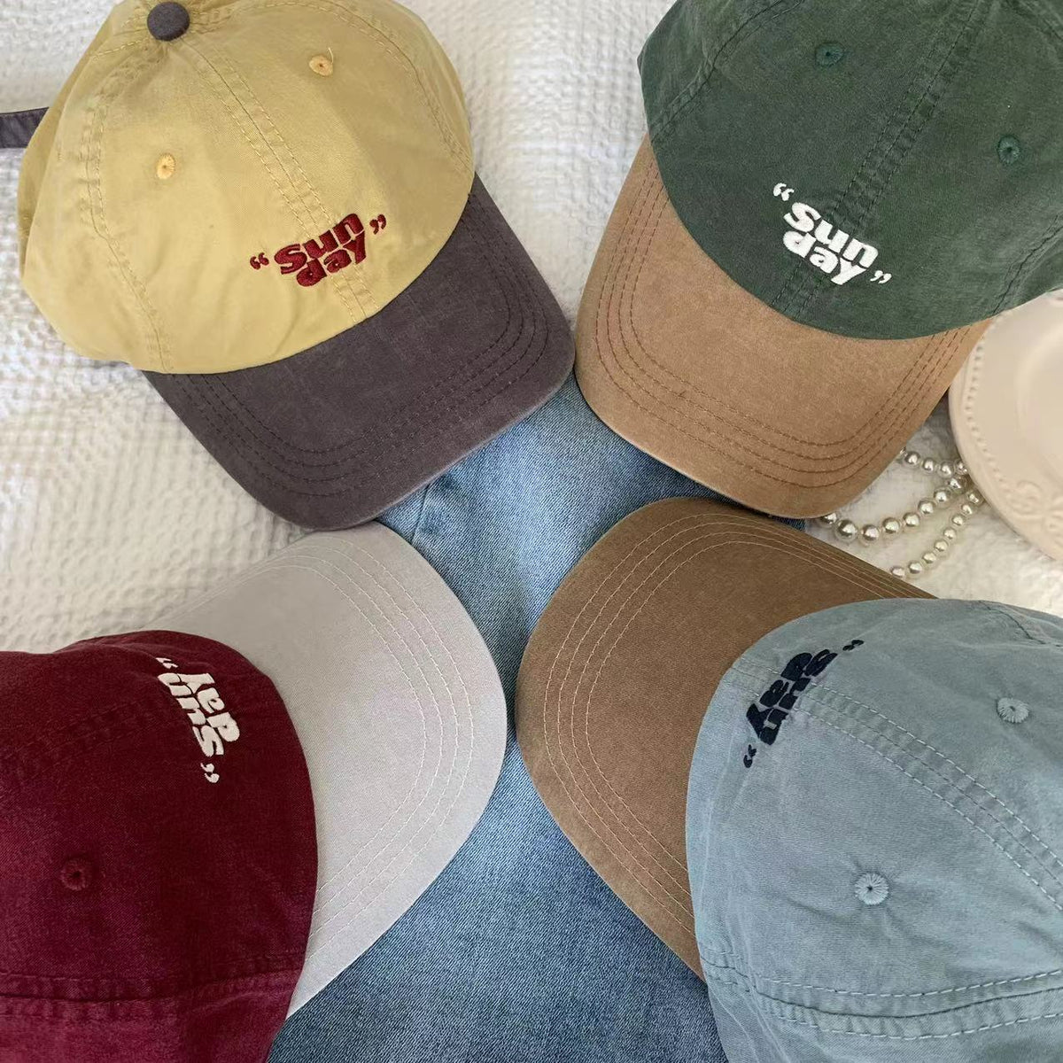 Assorted two-tone streetwear baseball caps arranged on fabric