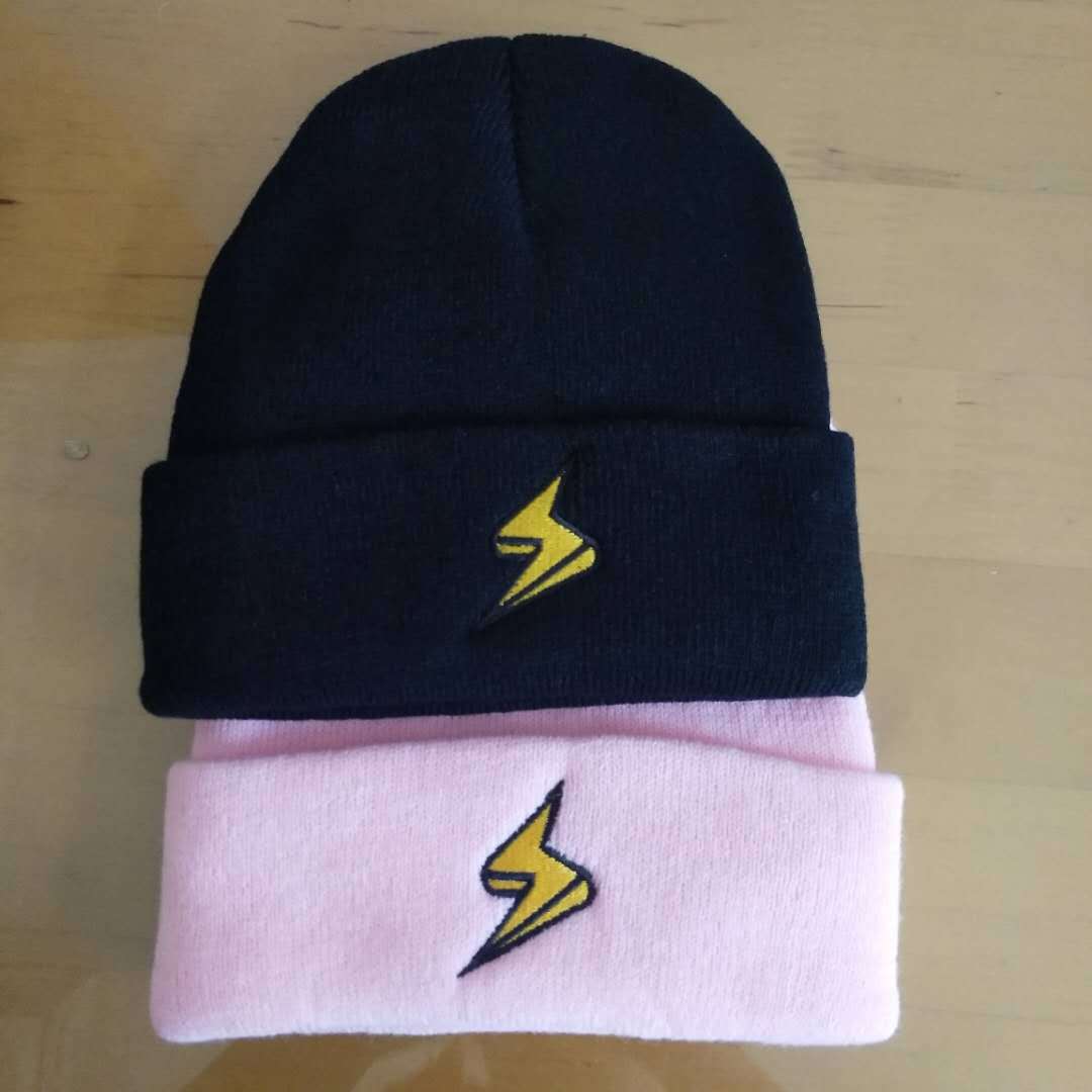 Black and pink lightning bolt embroidered beanies arranged together