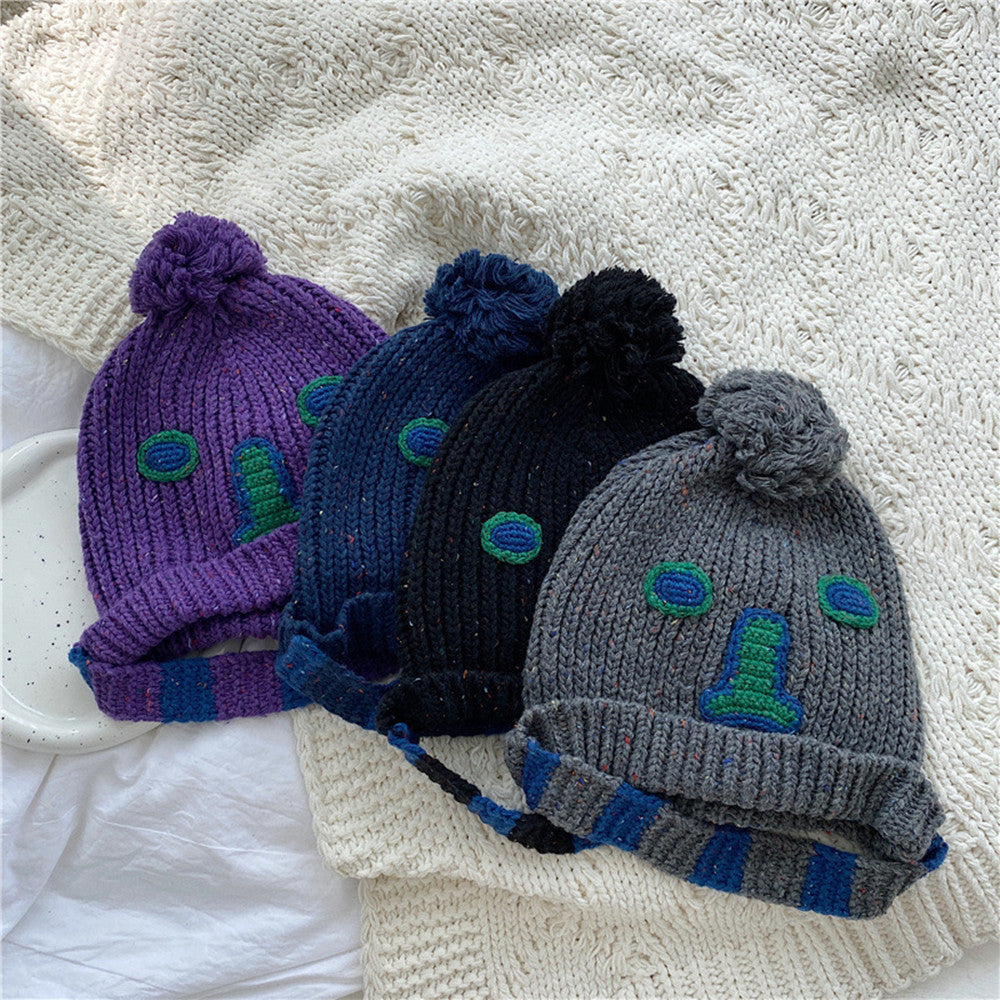 Unisex Cartoon Embroidered Pom Pom Knit Beanie — four cartoon face pom-pom beanies in purple blue black and gray