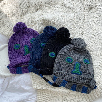 Unisex Cartoon Embroidered Pom Pom Knit Beanie — four cartoon face pom-pom beanies in purple blue black and gray