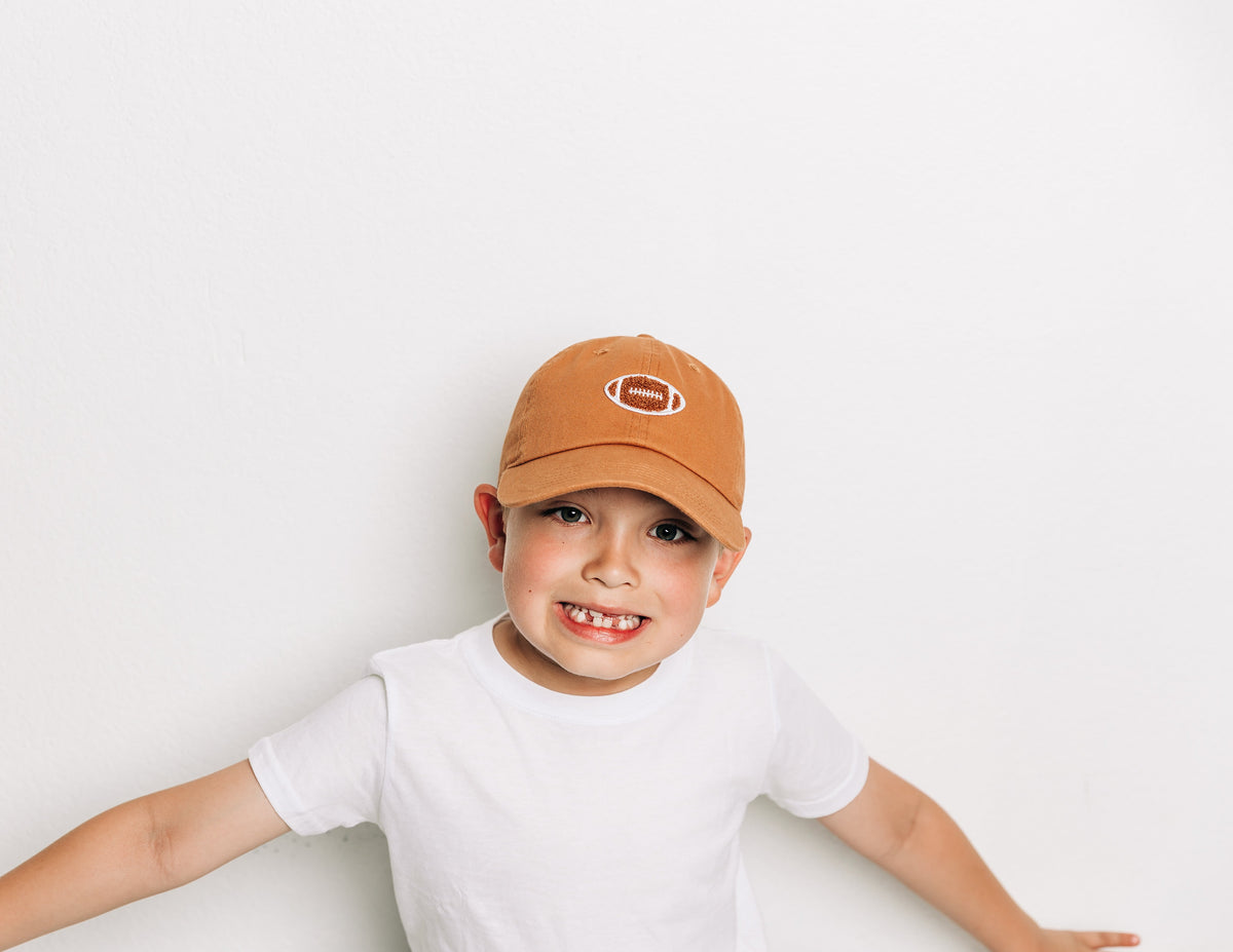 Rey To Z child wearing the Terra Cotta football-patch cap and white top