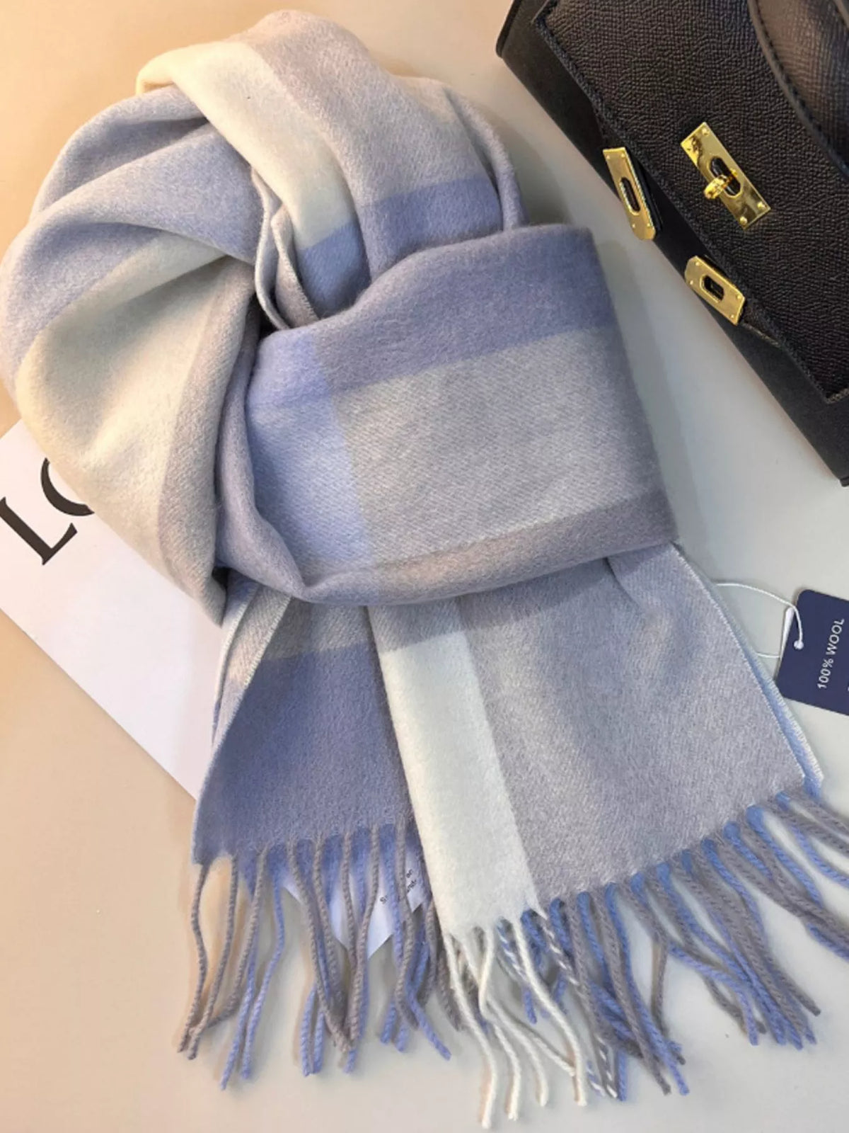 Unisex Plaid Scarf with Fringe — pale blue wool plaid scarf tied on a magazine