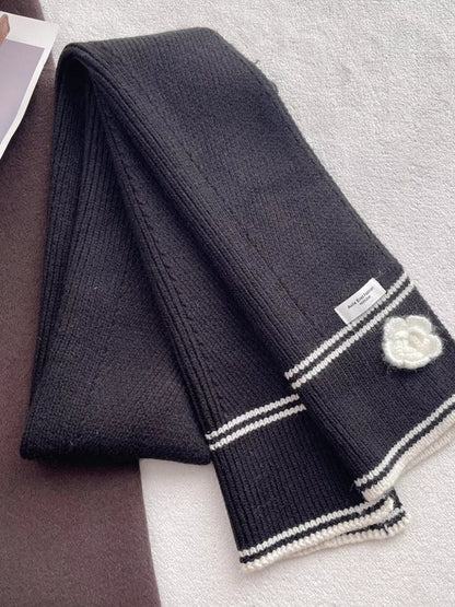 Women's Contrast Trim Knitted Scarf with Camellia Decor — black knitted scarf laid diagonally with decorated end visible