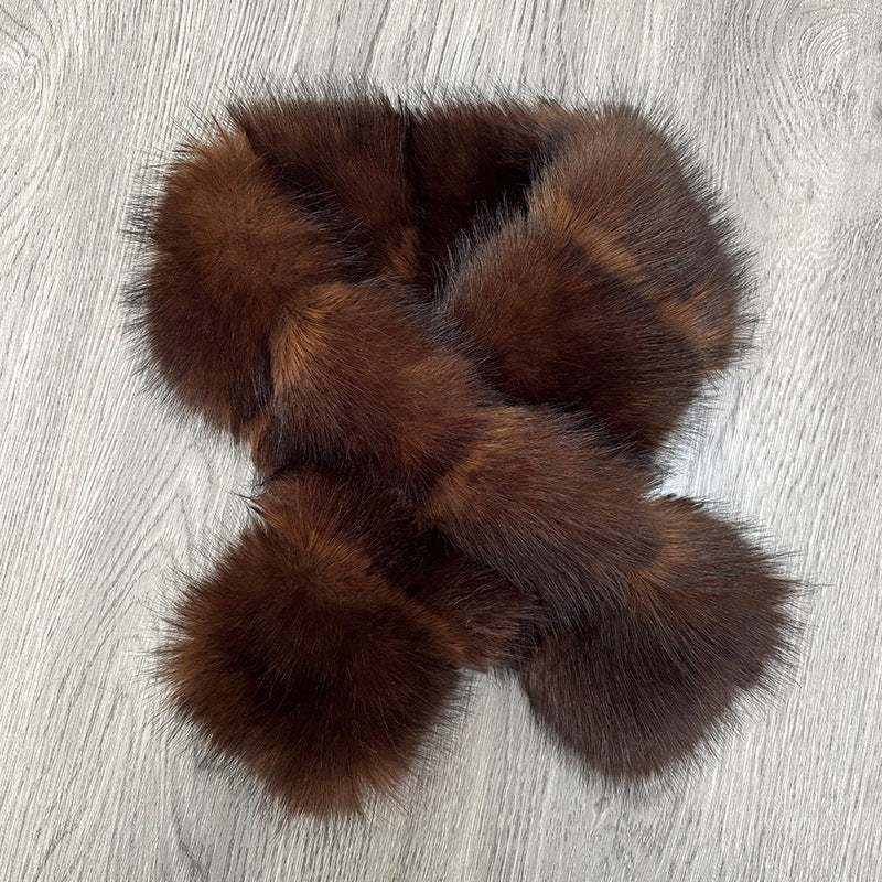 Dark brown plush crisscross scarf laid on a pale textured surface