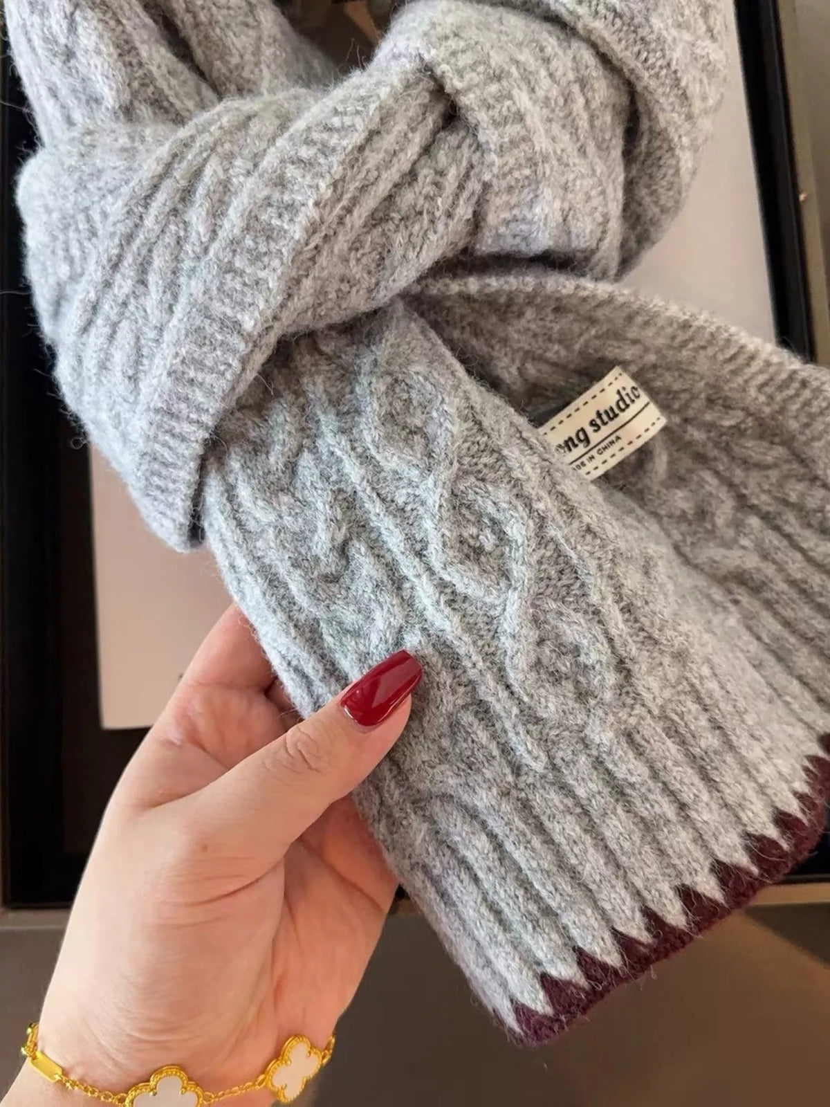 Unisex Cozy Cable Knit Scarf with Contrast Trim — hand holding the scarf to show raised cables and contrasting edge