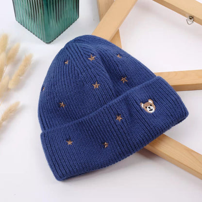 Blue knitted beanie with teddy bear face and small star embroidery