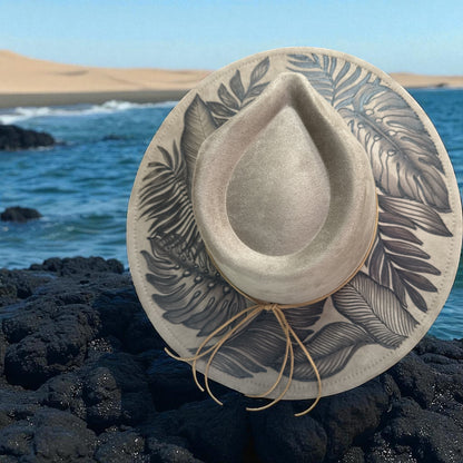Overhead view of the light taupe fedora with burned botanical brim artwork