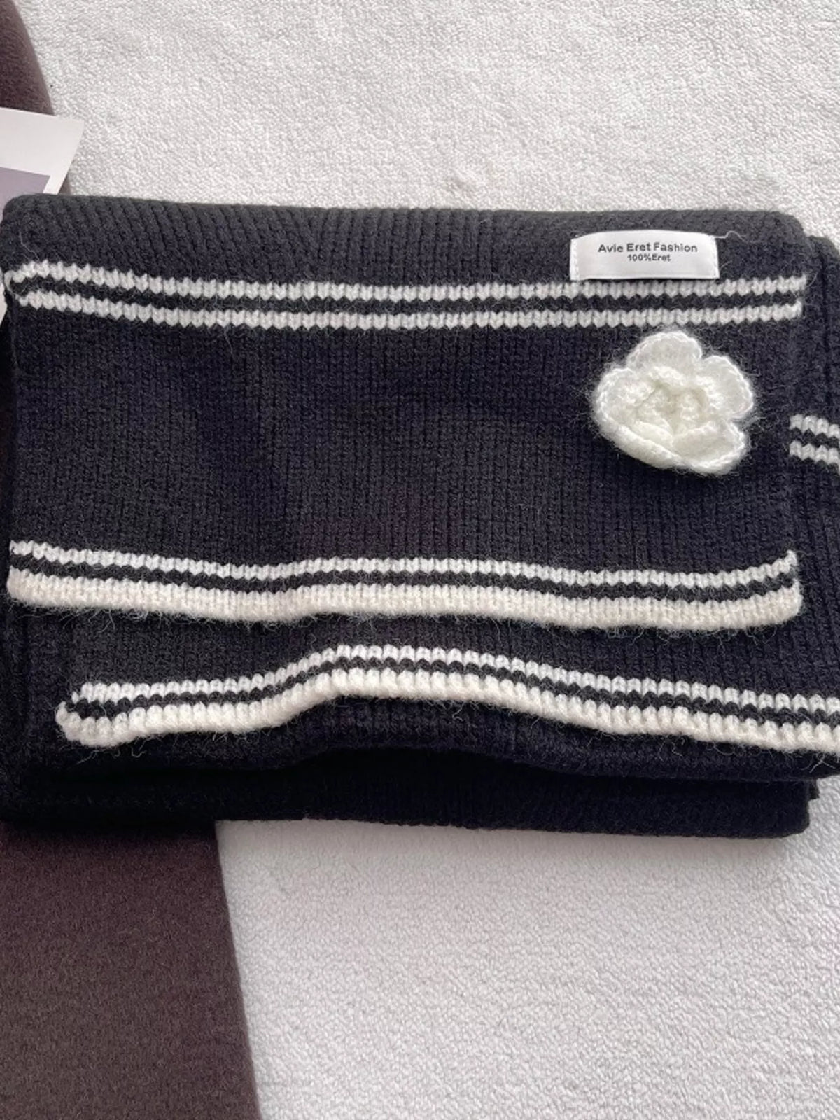 Women's Contrast Trim Knitted Scarf with Camellia Decor — folded scarf showing striped trim and pale flower detail