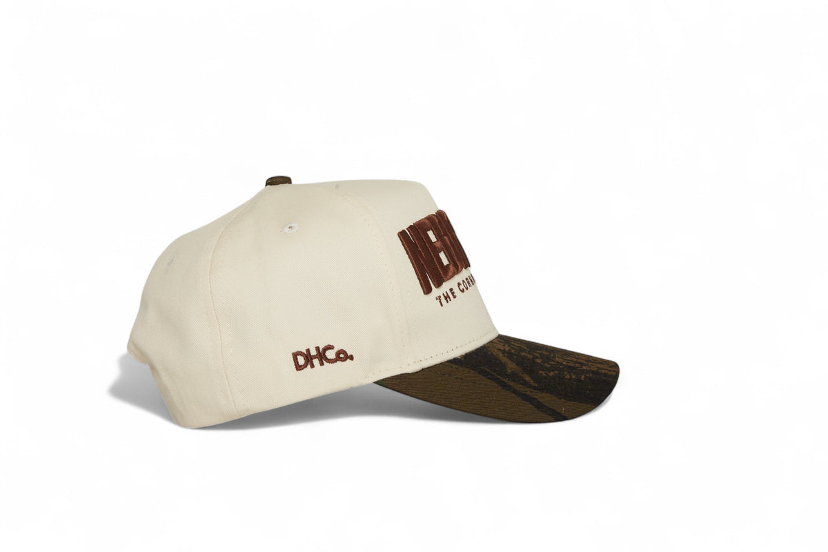 Side profile of the Destination Hat Co. Nebraska camo cap showing the curved bill and side logo