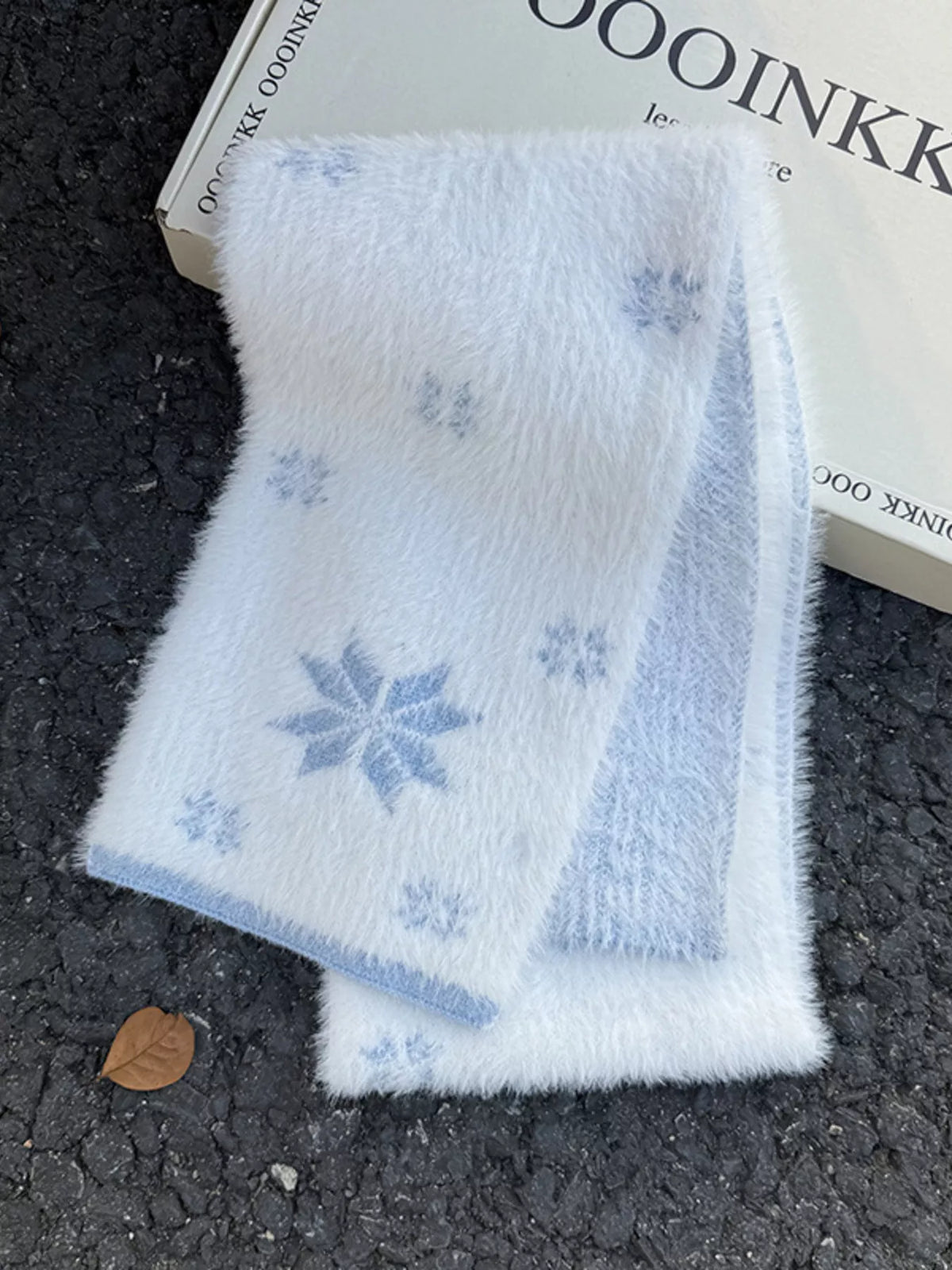 Unisex Snowflake Plush Knit Scarf — pale blue snowflake scarf laid flat on a dark surface