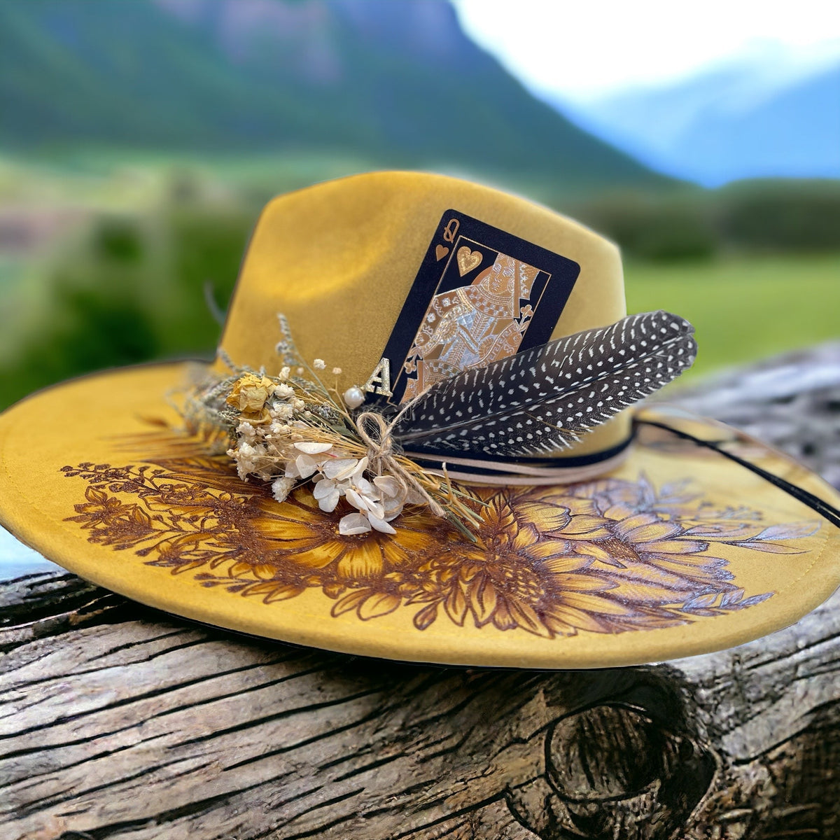 Mustard Piper Aurelia hat with burned floral artwork and decorative band, angled view