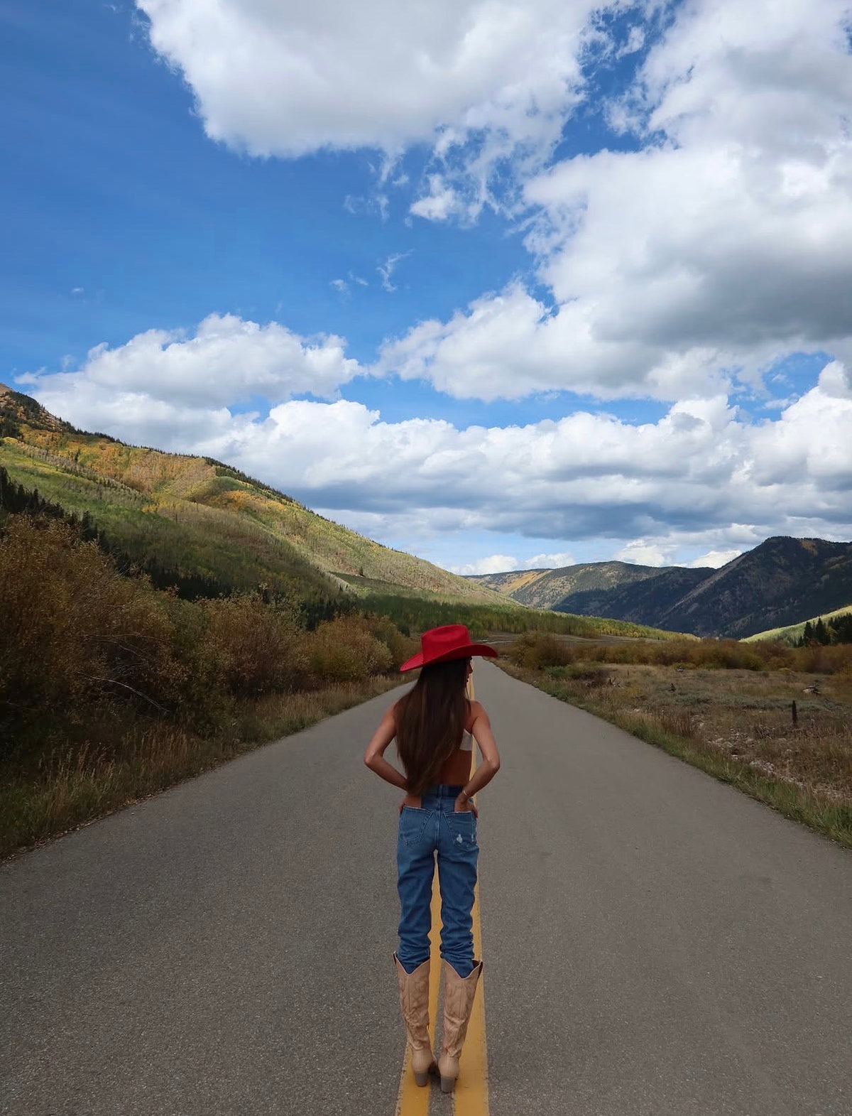 ASN Hats Dolly- Red red cowboy hat, full-outfit view on a mountain road