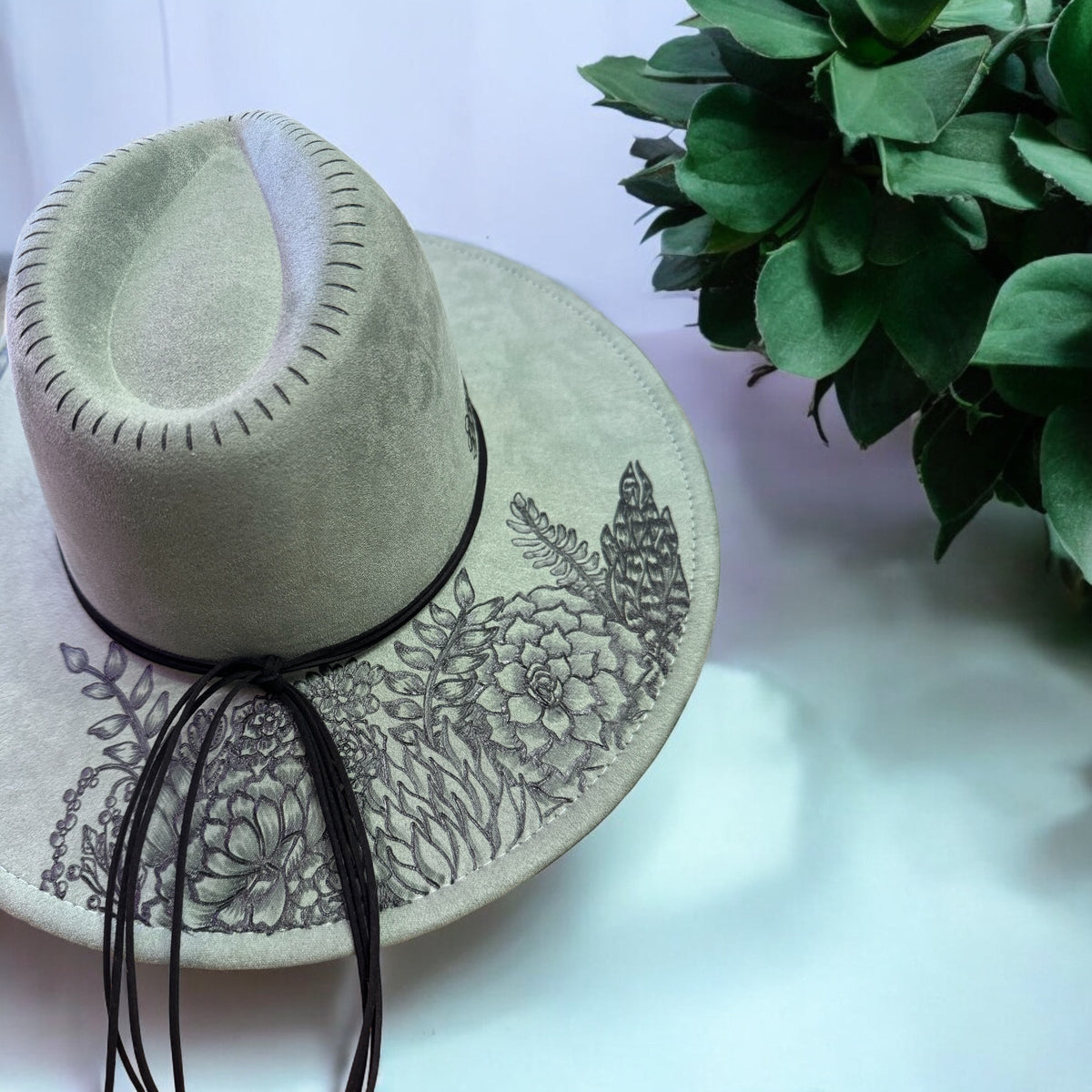 Rear view of the sage green Jade hat showing artwork around the crown