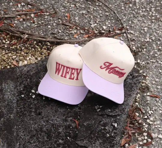 The Mad Hatter Company Mommy Snapback Hat, pink Mommy cap displayed beside another embroidered hat