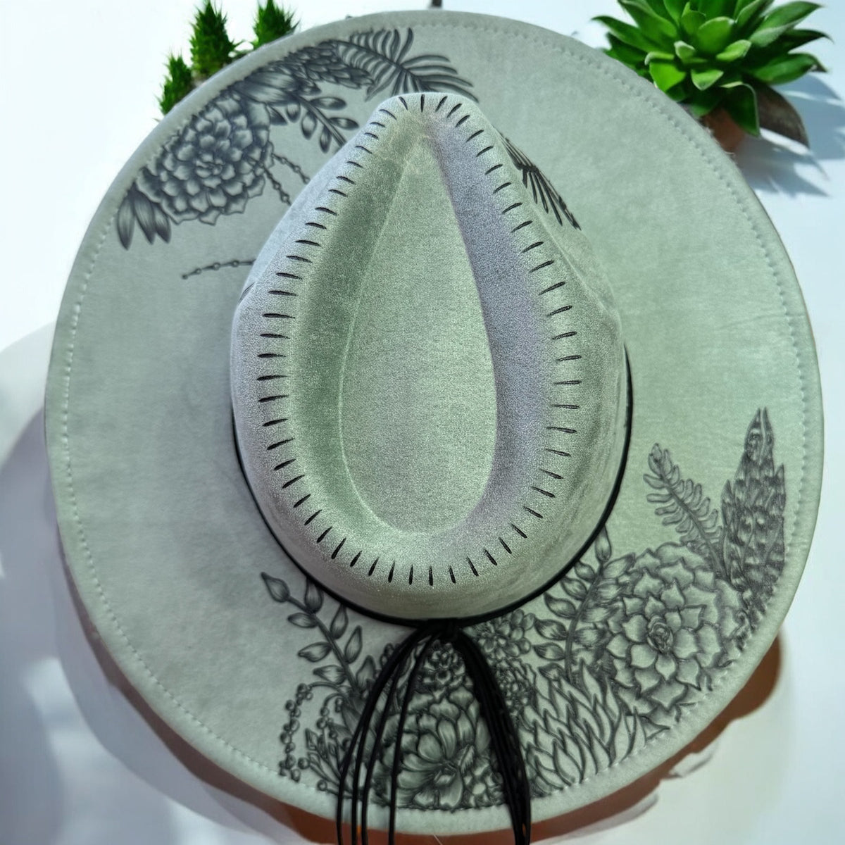 Sage green Piper Jade wide-brim hat with burned botanical artwork, overhead view