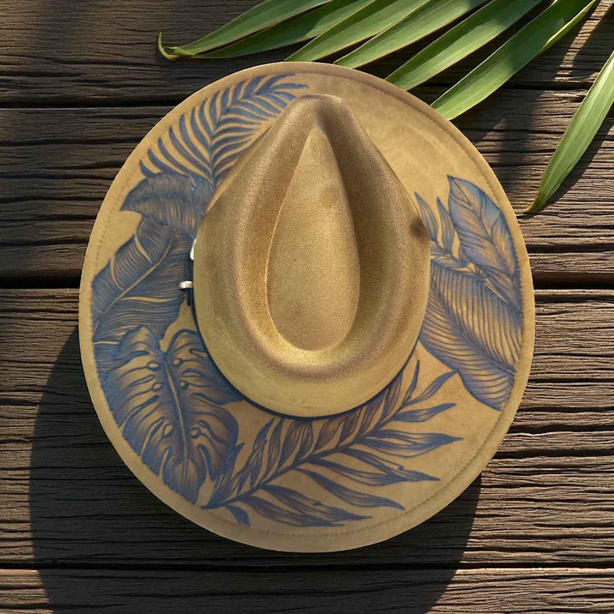 Khaki brown High Definition fedora shown from above against green leaves