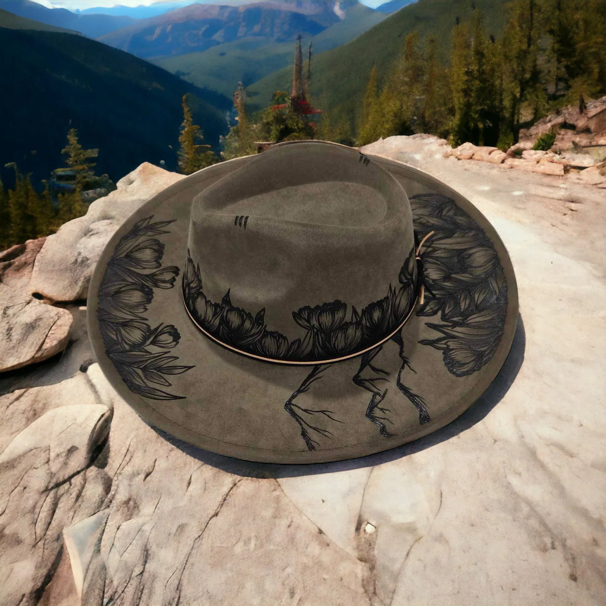 Rear angled view of the olive hat showing the mountain artwork around the crown