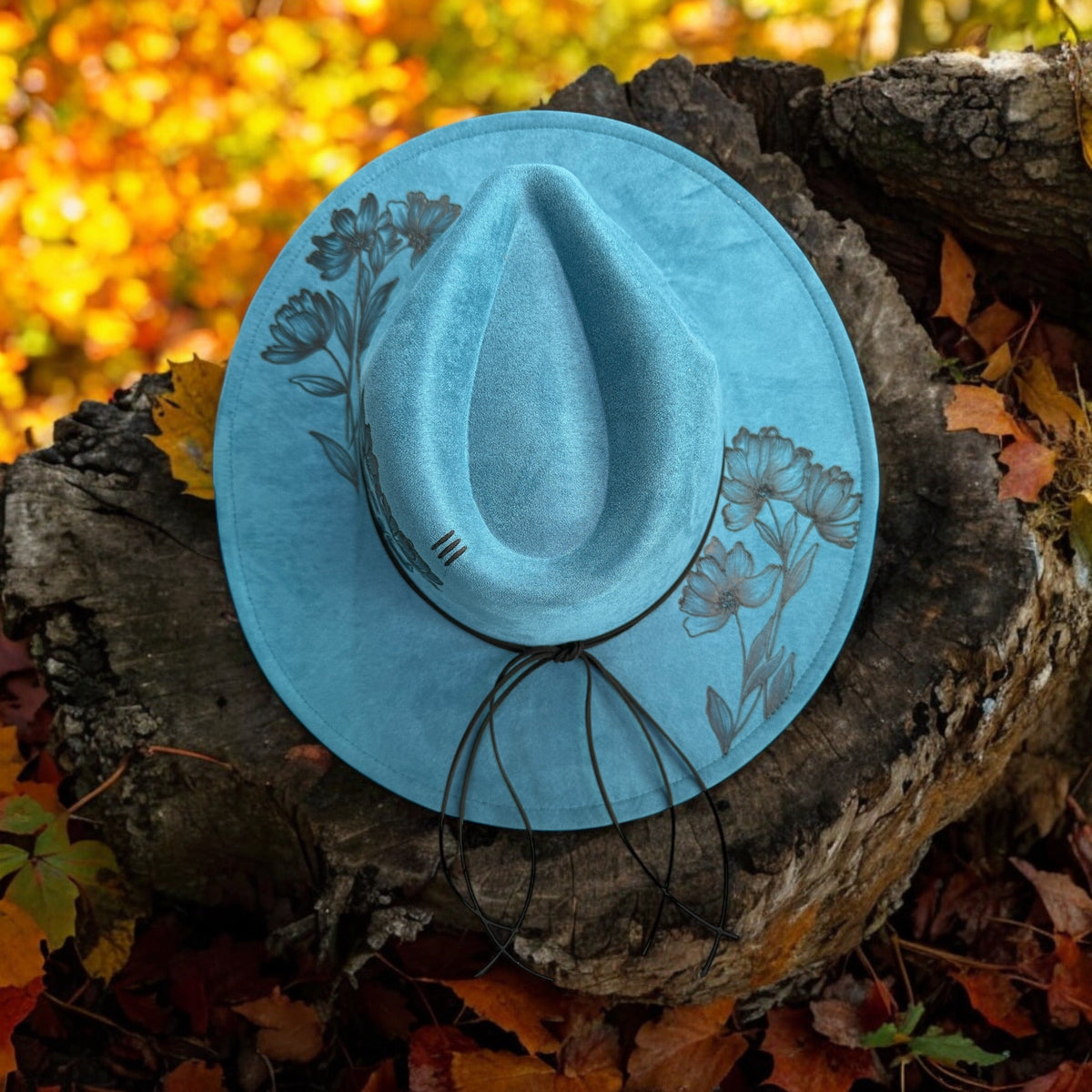 Native Petals hat tilted against an autumn woodland backdrop to show the brim artwork