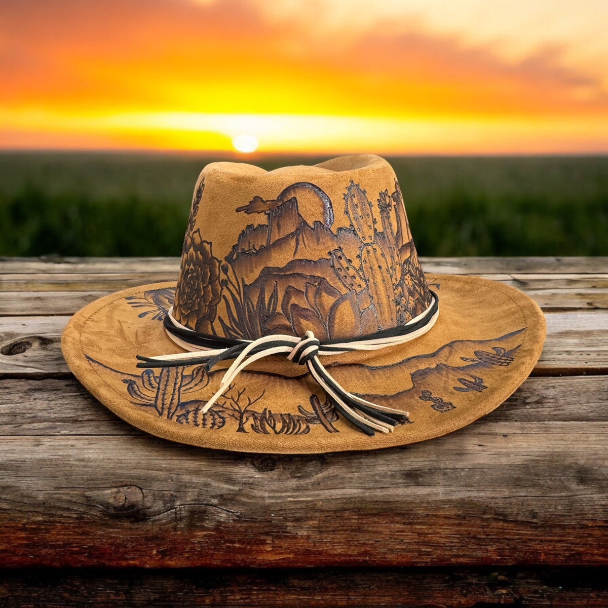 Front view of the Desert Sun hat with cactus artwork and decorative band at sunset