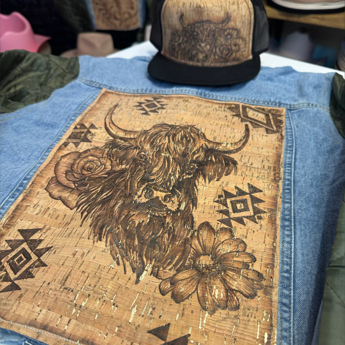 Close-up of the cork back panel with burned Highland cow, geometric, and floral designs