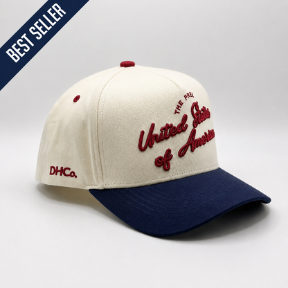 Destination Hat Co. U.S.A. script cap with beige crown and navy bill, angled view