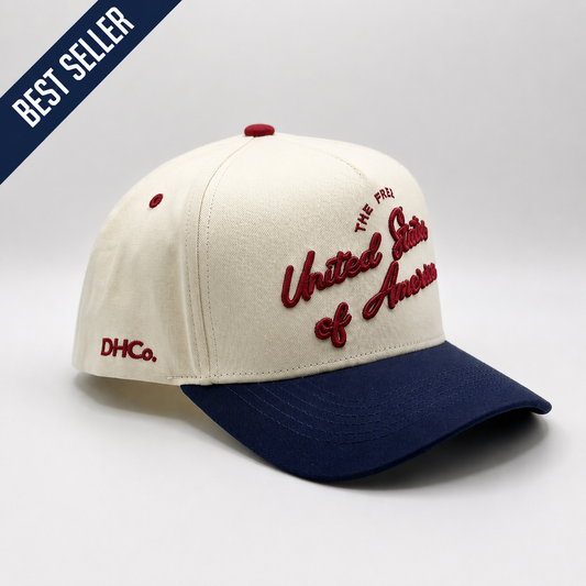 Destination Hat Co. U.S.A. script cap with beige crown and navy bill, angled view