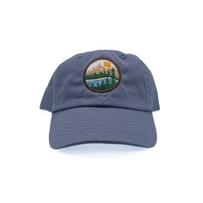 Front view of Rey To Z Mountain Baseball Hat in Dusty Blue showing round mountain landscape front patch