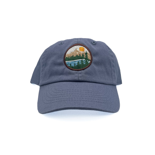 Front view of Rey To Z Mountain Baseball Hat in Dusty Blue showing round mountain landscape front patch