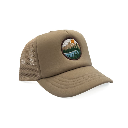 Angled view of Rey To Z Mountain Trucker Hat in Khaki showing the curved bill and mesh panels