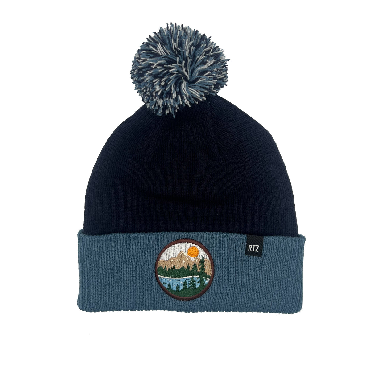 Rey To Z Mountain Pom Pom Hat in Navy & Blue showing round mountain landscape patch on the cuff and a pom-pom top