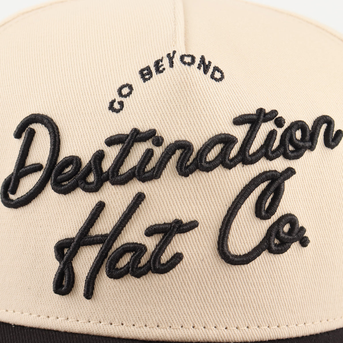 Close-up of the black Destination embroidery on the beige crown