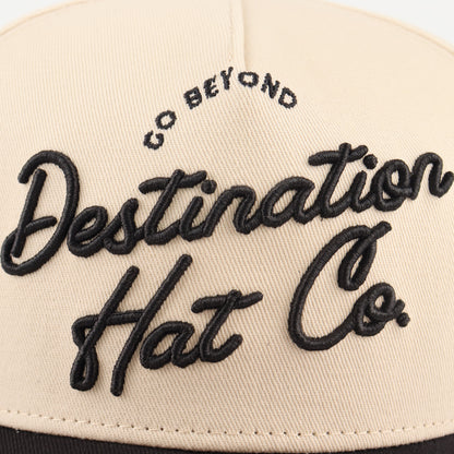Close-up of the black Destination embroidery on the beige crown