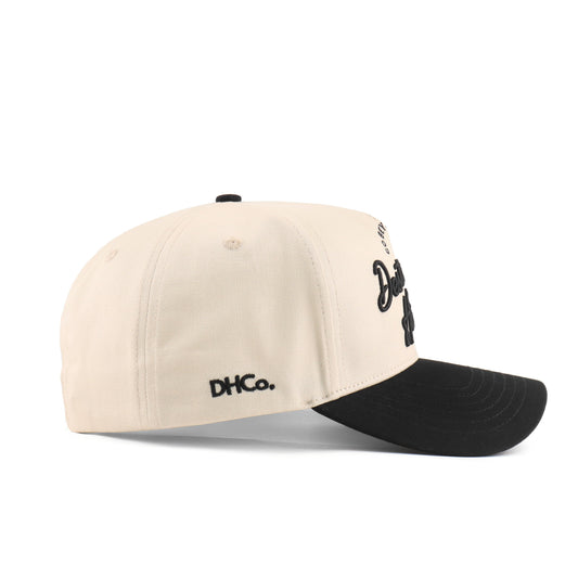 Side profile of the Destination Hat Co. Baton Rouge script cap showing the curved bill and side logo