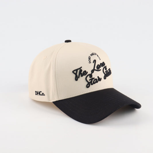 Destination Hat Co. Lone Star script cap with beige crown and black bill, angled view