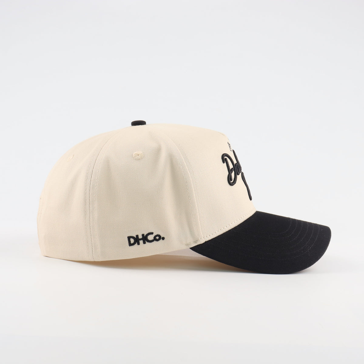 Side profile of the Destination Hat Co. Dallas script cap showing the curved bill and side logo
