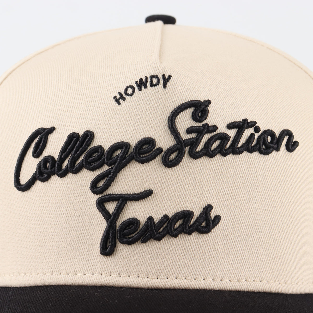 Close-up of the black College Station embroidery on the beige crown