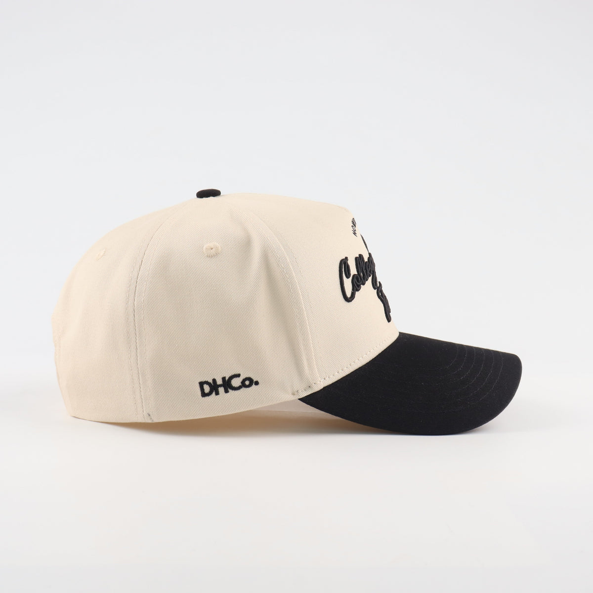 Side profile of the Destination Hat Co. College Station script cap showing the curved bill and side logo