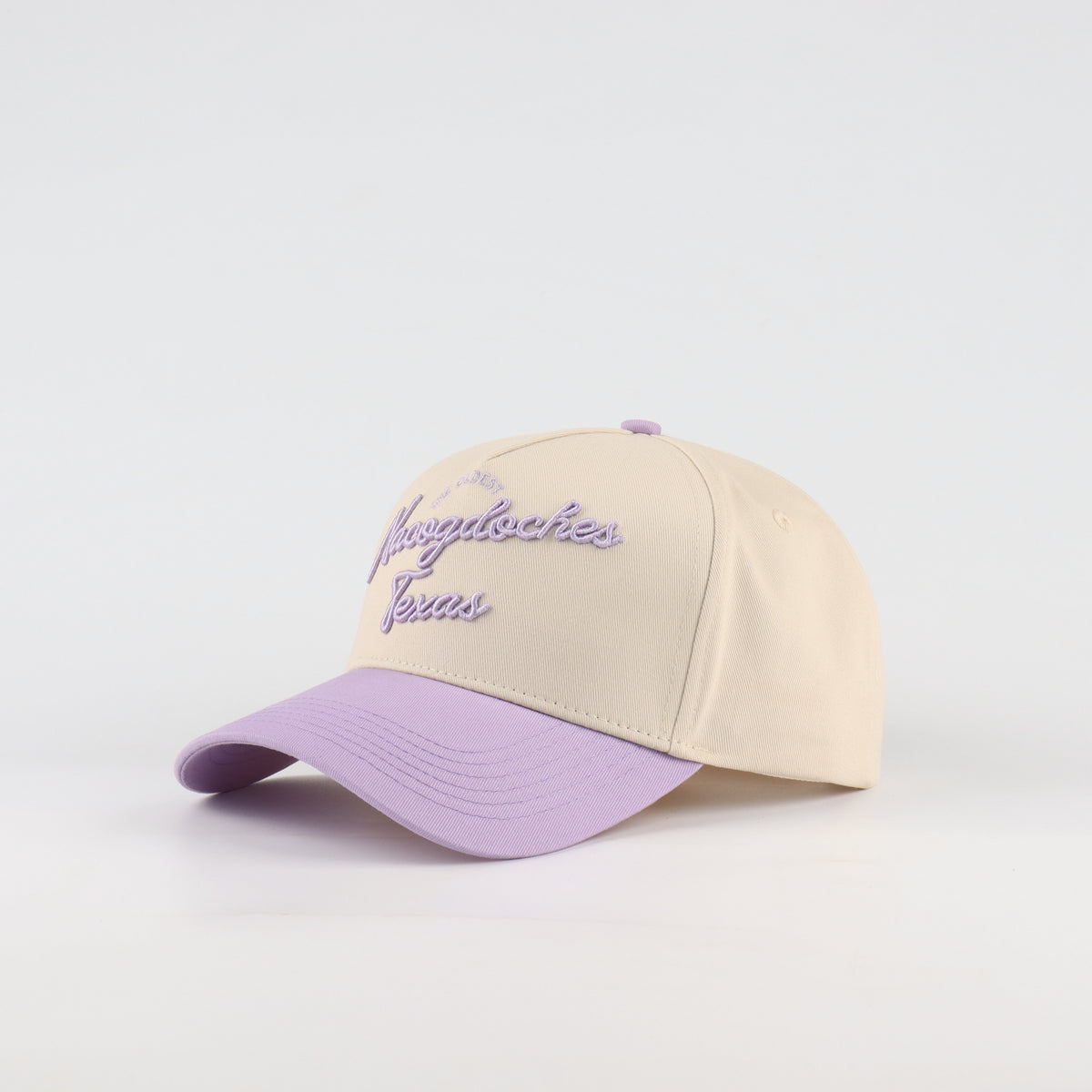Opposite angled view of the Destination Hat Co. Nacogdoches script cap showing the purple lettering