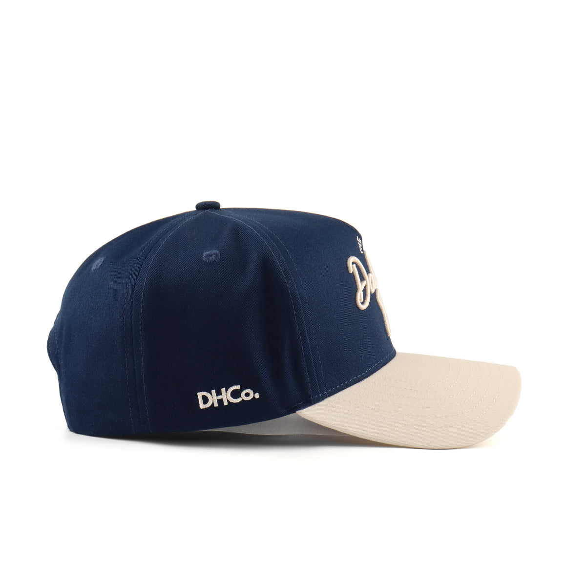 Side profile of the Destination Hat Co. Dallas script cap showing the curved bill and side logo