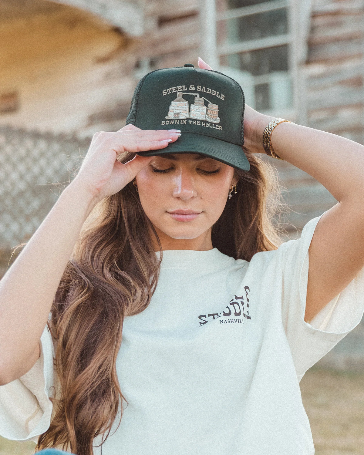 Model adjusting the black Stillhouse trucker hat outdoors