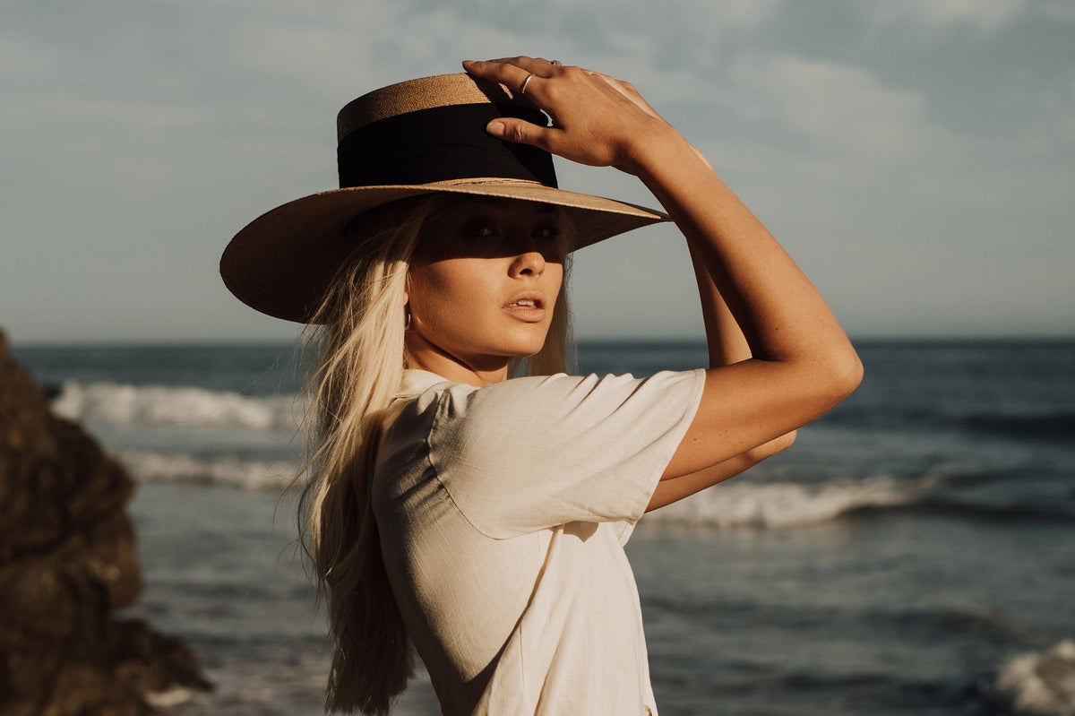 ASN Hats Isla Bonita natural boater hat, worn with a beige outfit by the water
