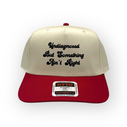 Natural and red Something Ain't Right cap with black script embroidery