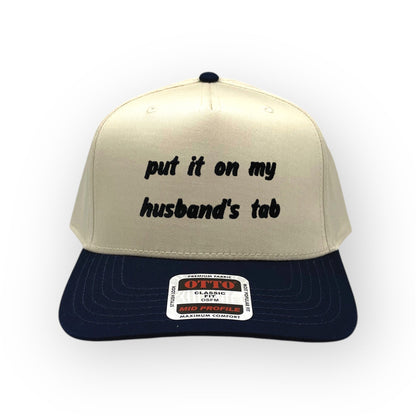 Front view of Put It on My Husband's Tab cap by Horizon Hat Co. in Natural/Navy showing put it on my husband's tab front embroidery