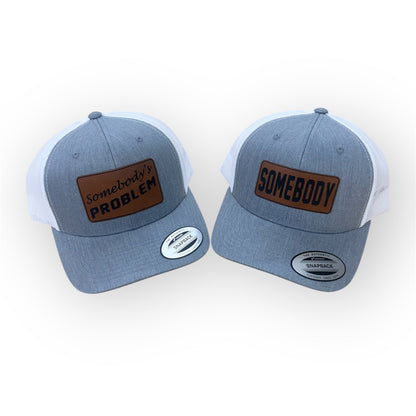 Two Heather Gray and White Horizon Hat Co. trucker hats with SOMEBODY and Somebody's PROBLEM Rawhide patches